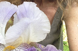 iris blossom in front of woman in sleeveless green shirt