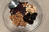 A mixture of walnuts, almonds, peanuts, pistachios, prunes and blueberries, ready to add chia seeds and skim milk.