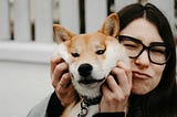 Woman holding a dog and pinching its cheeks for the camera