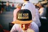 man wearing “love your neighbour” cap