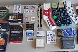 A table in a hotel room covered in socks, stickers, food, and books collected from various vendors throughout the conference
