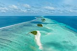 Crystal-clear turquoise lagoon surrounded by lush palm trees and white sand beach under golden afternoon sunlight
