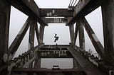 A person somersaulting over a bridge over a lake.