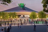 The Climate Pledge Arena glows in Seattle at dusk with solar powered LED lights, as pedestrians stream in time-lapse across its wide outdoor plaza.