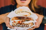 photo of women holding large sandwich up to eat