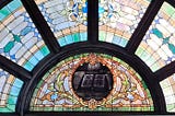 Stained glass church window with open bible in center