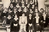 A black and white photo of students with their teacher sitting on the front steps of Varndean High School in 1981. The students are wearing school uniform.