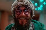 Smiling, bearded man in stocking hat with glasses that look like a bicycle