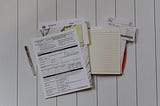IRS tax forms and yellow note pad on a writing surface
