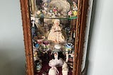 An ormolucabinet filled with porcelain and old dolls.