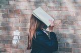 School girl holding book over head