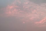 A soft pink evening sky with layered clouds fading into grey — a quiet, hazy moment just before dusk.
