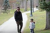 man and small boy standing in park