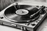 Charcoal drawing showing  a record player and black vinyl playing on it.