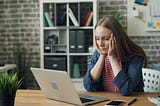 A lady staring at the laptop looking upset.