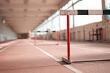 Close up of a hurdle with a runner in the far distance, blurred.