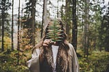 Woman Standing at Woods Holding Green Plant