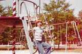 kid in striped shirt, bowl-cut hair, sitting on steps to playground equipment