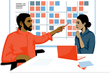 Illustration of two colleagues collaborating sitting at a table with a laptop in the foreground and a whiteboard with sticky notes in the background.