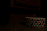 A ceramic cat food bowl sits in a dimly lit room