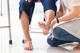 A nurse examining an elderly patient’s foot