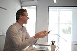 Photo by Andrea Piacquadio: https://www.pexels.com/photo/smiling-adult-businessman-at-table-with-gadgets-holding-presentation-3760371/