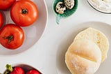 A table with vegetarian food- tomatoes, breads, etc