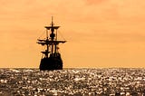 A tall ship sillhoutted against an orange sky