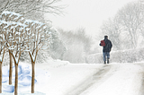 Man on a meditative walk in gentle winter snow contemplating the meainngs of winter and life