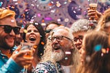 Happy people celebrating a special occasion with confetti in the air and drinks in hand.