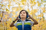 child listening to music through headphones with eyes closed