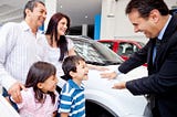 A salesperson addressing a family at a car showroom