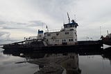 A Russian paddle-wheel ferry stands next to a river bank.