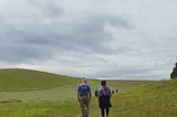 Man and woman walking in a landscape.