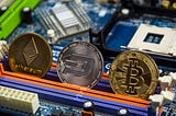 Three cyprotcurrency coins sitting on a circuit board