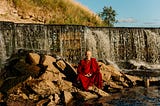 A peaceful monk, free from worrying, meditates by a river.