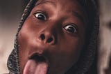 A picture of a black young person with tongue out in mockery