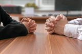 Hands coming together at a work desk to negotiate