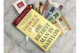 The Richest Man in Babylon book on top a stack of cash