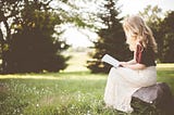 Woman reading book in meadow.