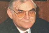 Picture of face of smiling man in his late fifties or early sixties, wearing glasses. Writer’s father
