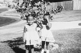 Joy Macko and her twin sister standing together outside as toddlers