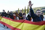Photograph showing contemporary Francoists with right arms raised in the fascist salute while carrying and red and yellow Spanish flag banner.