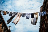 Washing hanging from a clotheslines between two buildings with a backdrop of blue sky and clouds