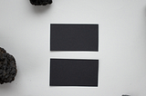 Black rocks and black rectangles on porous white paper