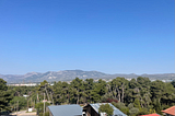 A view from my window at Anixi Hotel overlooking a stretch of sandy mountains, pine trees, and tin rooftops.