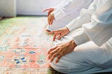 Two individuals doing Tassbih in Masjid or mosque, both are performing the daily prayer.