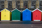 A photo of four wooden booths, each with different colour.