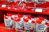 Store rack of a variety of Kinder chocolate candies, including Kinder Eggs.