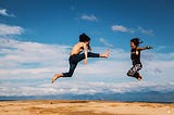Man and woman jumping in the air and laughing.